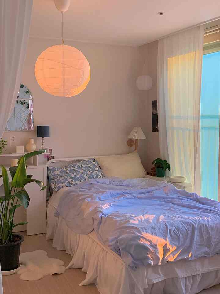 White and blue toned bedroom featuring soft curtains and plants, creating a cozy atmosphere
