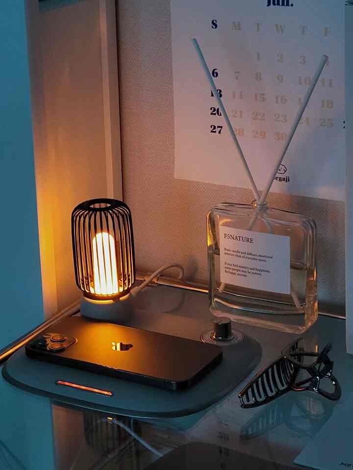 Cozy bedroom desk with warm mood lamp, wireless charger, and diffuser creating a tranquil atmosphere