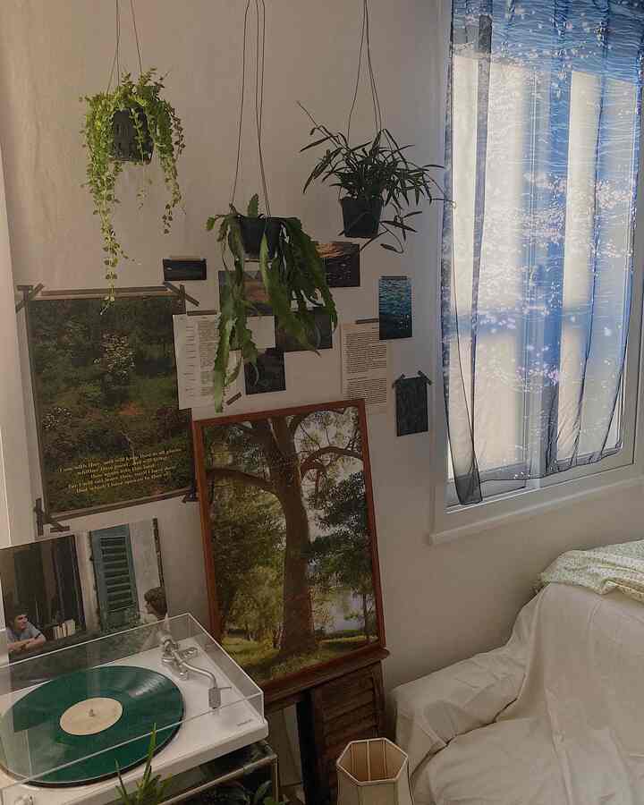 白と茶色のトーンのワンルーム、ヴィンテージポスターやフロアランプ、ターンテーブル、植物が配置された雰囲気のあるインテリア