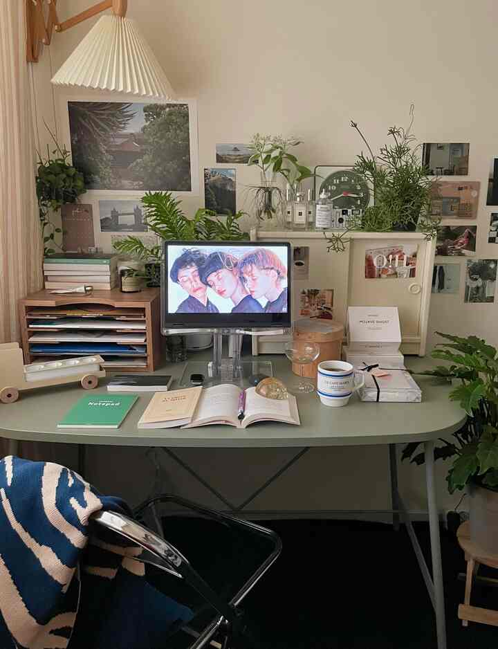 ナチュラルトーンのホームオフィス、グリーンのデスクと植物、本、デジタルモニターが置かれた雰囲気のある書斎