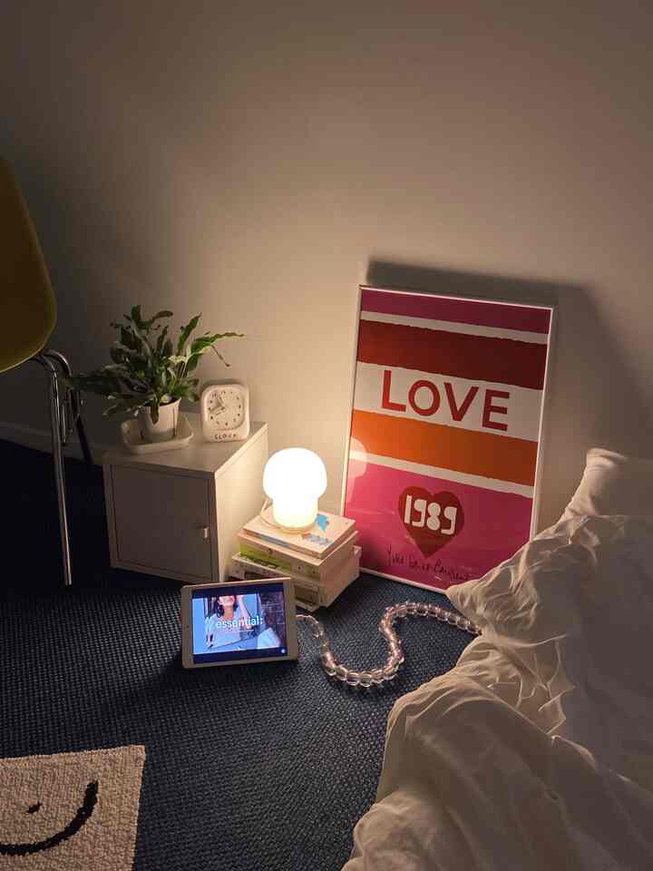 白とネイビーの色調の寝室、デスク横にランプと額縁が配置された雰囲気のあるインテリア