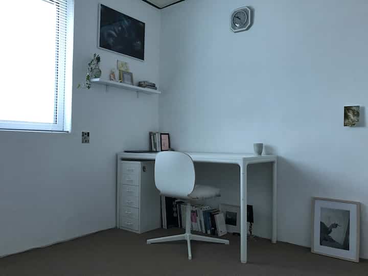 Small home office in white and beige tones featuring a minimalist desk and chair with a clean, uncluttered atmosphere