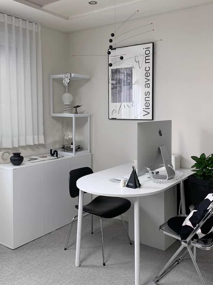 White and black toned studio home office featuring minimal modern desk and unique shelf arrangement with clean atmosphere