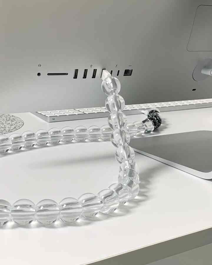 Minimal white-toned desk space featuring a transparent pearl code accessory on a clean workspace