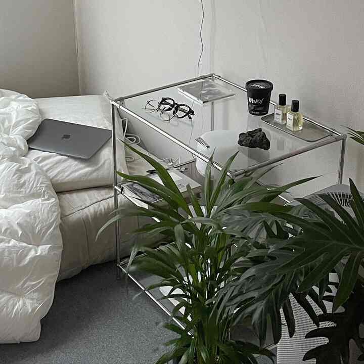 シンプルでモダンな白を基調とした寝室、透明なシルバーの棚とグリーンの植物がきれいに配置された空間