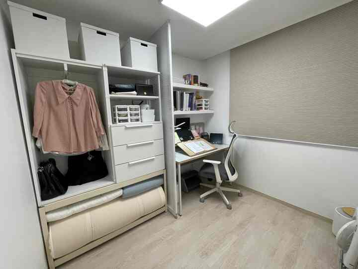White and beige toned student room featuring organized desk and storage units with a simple, focused atmosphere