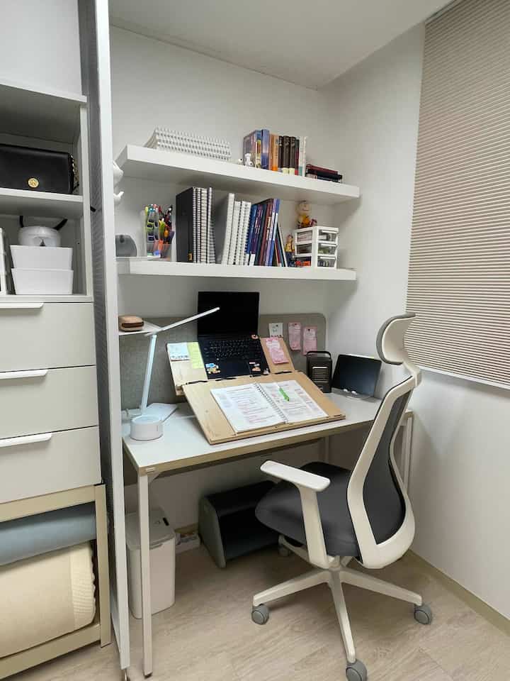 White-tone compact home office featuring a desk and office chair with an organized remote work setup