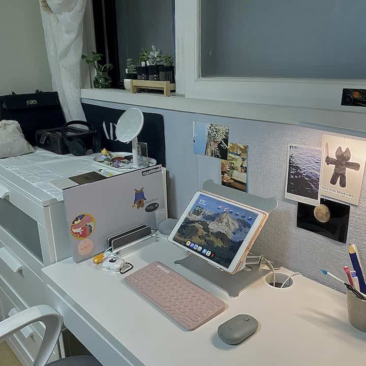 A simple home office study in white and gray tones, featuring a desk with an iPad and keyboard in a compact room