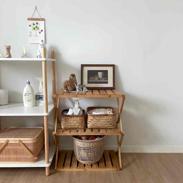 Simple storage space with white walls, natural wood tone shelving, and rattan baskets creating a harmonious look
