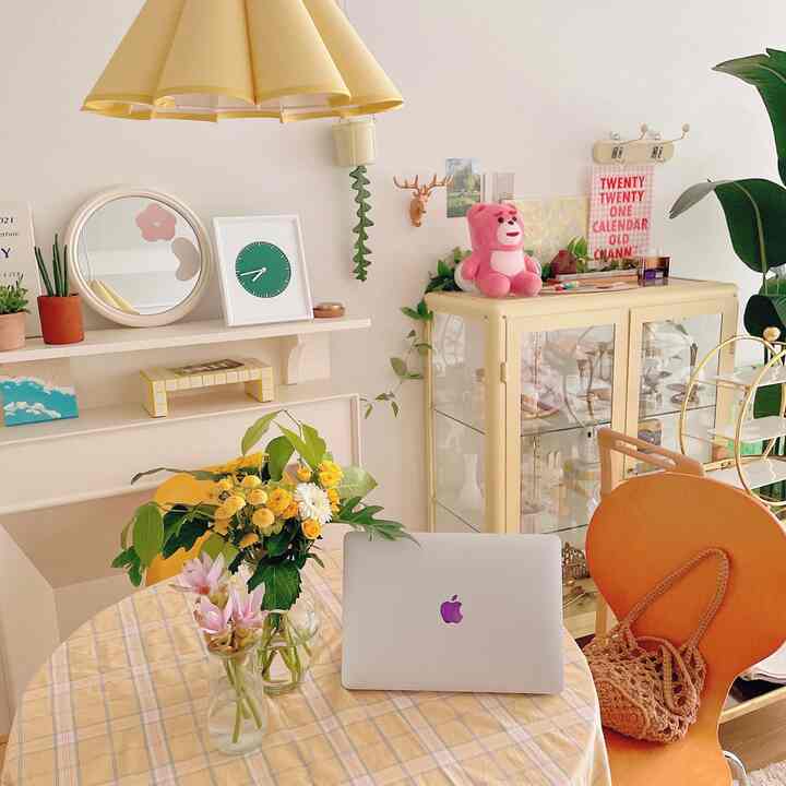 Yellow-toned living room with natural plants featuring a home office and dining area setup