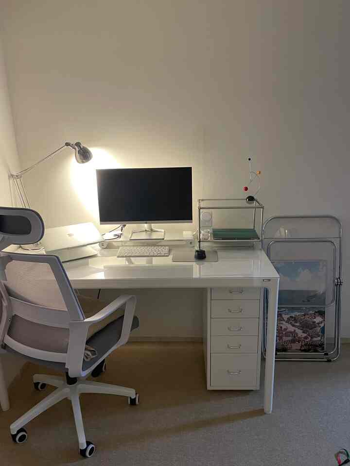 White-toned home office space featuring a monitor, desk, and office chair arranged neatly in a simple workspace