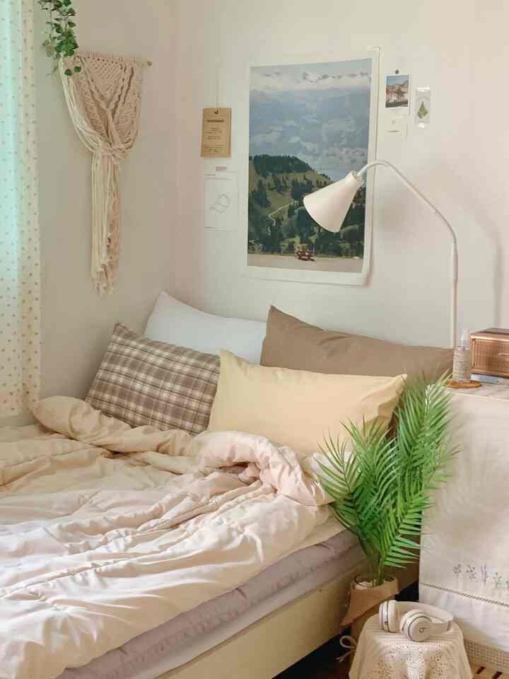 ナチュラルなベージュトーンの寝室、秋の雰囲気を感じさせる居心地の良い寝具と緑の植物が配置されたインテリア