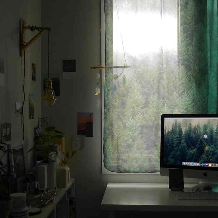 White and green toned study featuring an iMac desk and forest patterned fabric curtain, creating a nature-inspired calm space