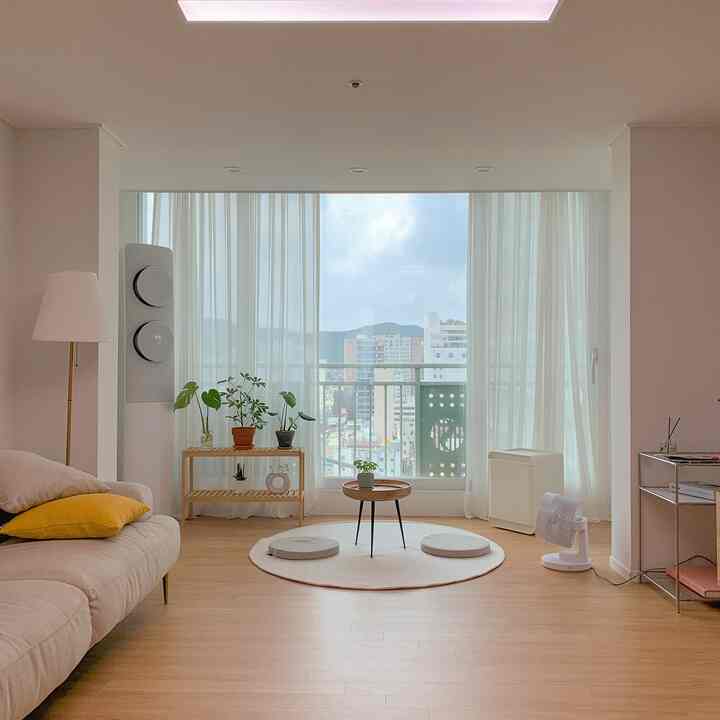 Bright living room with white and wood tones featuring a round rug and floor sitting table in a cozy, simple setting