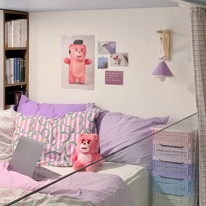 A lavender and white toned bedroom featuring a pink stuffed bear and pastel storage boxes with a cozy atmosphere