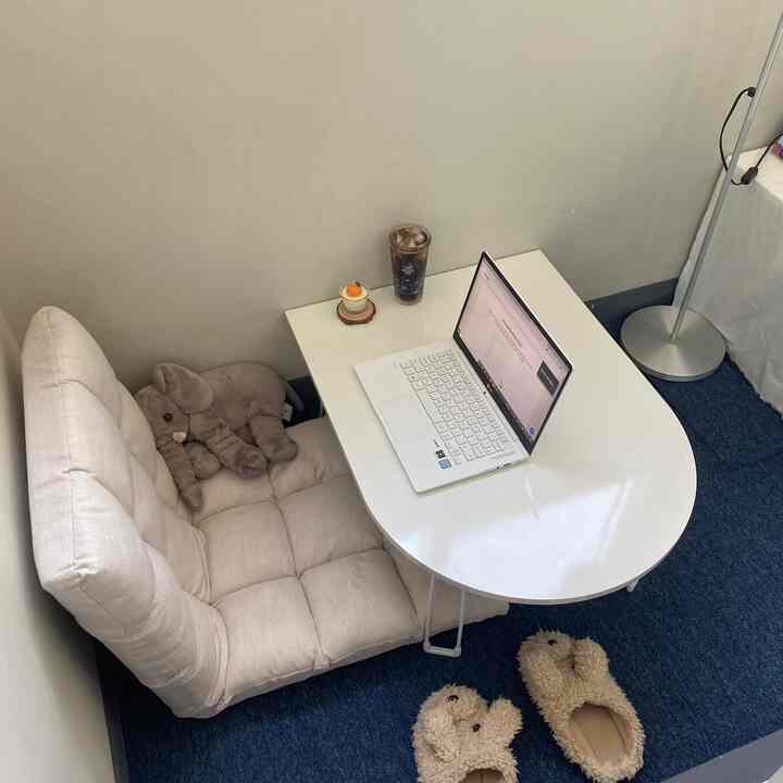 ホワイトとネイビートーンの狭いベランダ空間、U字型の楕円テーブルと柔らかい座椅子が置かれた雰囲気のあるホームオフィスインテリア