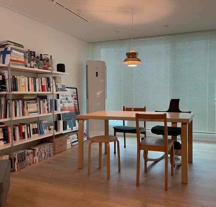 Natural wood-tone study and dining room featuring bookshelf-lined wall and wooden table with chairs