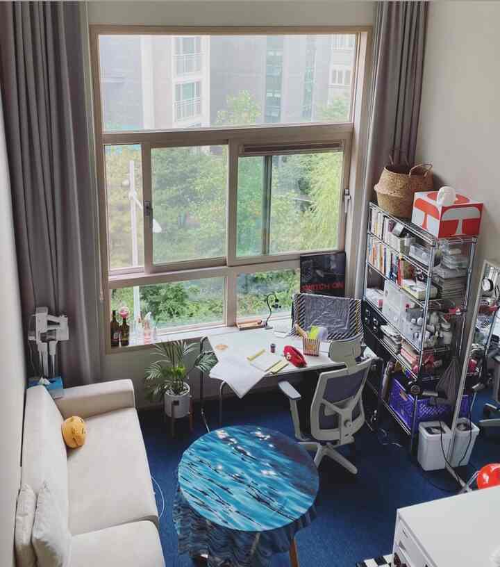 白と青のトーンが調和したコンパクトなホームオフィス空間、デスクとオフィスチェア、ソファ、棚が配置された雰囲気のあるインテリア