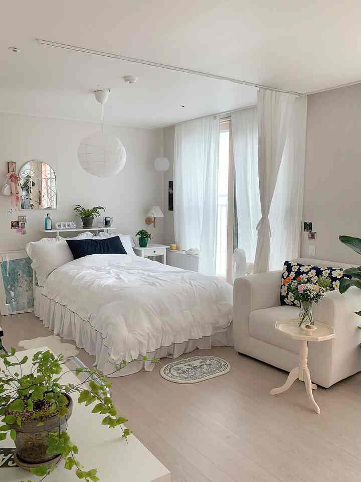 ホワイトとネイビーの調和が美しい寝室、フリル付き寝具と小さな観葉植物が配置された雰囲気のあるインテリア