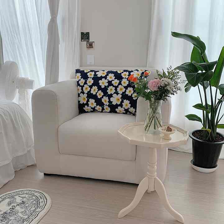 Soft white tone living room featuring floral cushion and fresh flowers, creating a simple and natural atmosphere