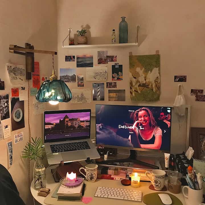 Warmly lit modern home office desk space featuring vintage posters and cozy candles