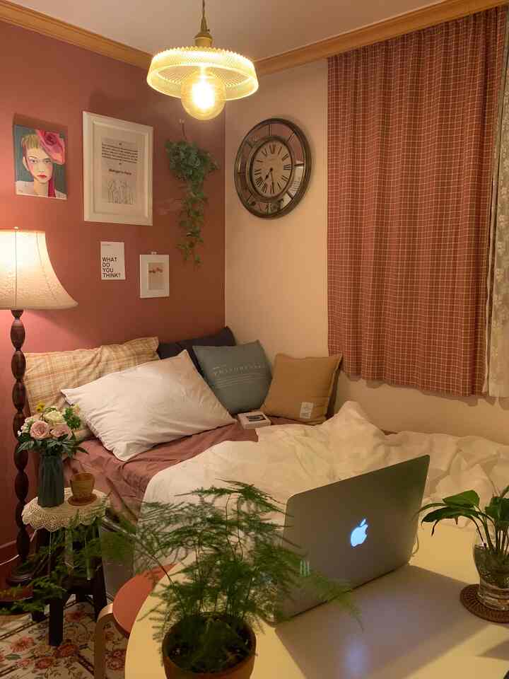 Warm brown and natural toned bedroom featuring a bed, pillows, floor lamp, curtains, and plants creating a cozy atmosphere