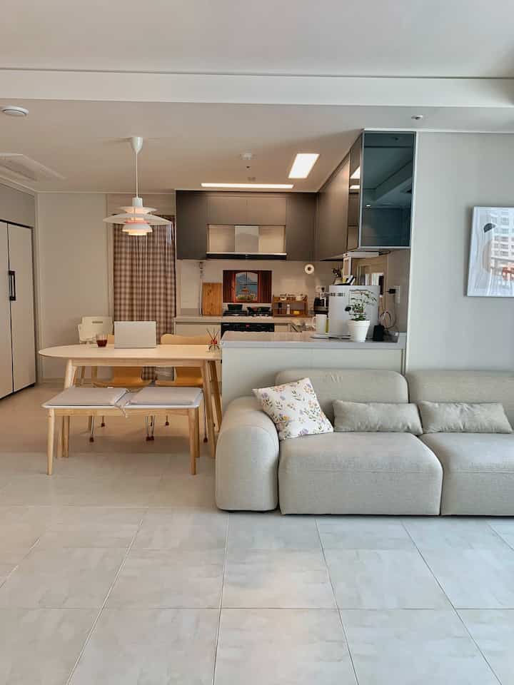 Beige-toned living room and kitchen with creamy sofa and wooden dining table, creating a harmonious natural modern interior