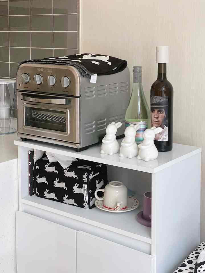 White-toned compact kitchen cabinet topped with a toaster oven and rabbit-shaped decor in a neat kitchen space