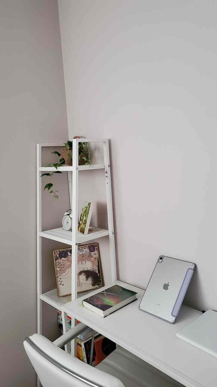 Soft white and natural-toned small room featuring a white desk and shelf, creating a simple home office space