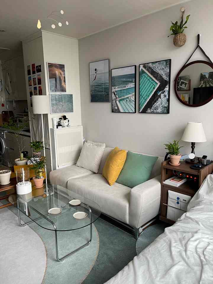 White and walnut-tone studio living room featuring transparent sofa table and vibrant plants in a natural modern style