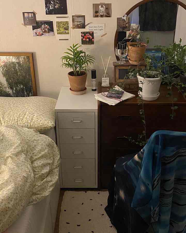 ベージュ調の落ち着いた寝室、木製の化粧台と植物が置かれた収納家具が配置された自然の雰囲気のあるインテリア