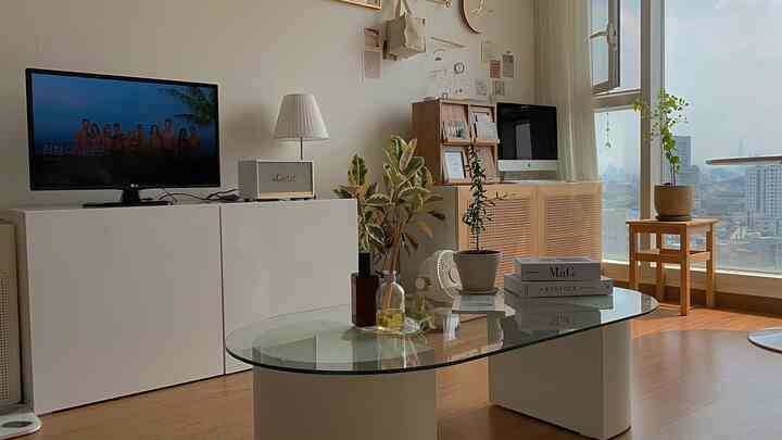 白い壁と木目調家具、植物インテリアが調和したワンルームのリビング、自然でモダンな雰囲気の空間