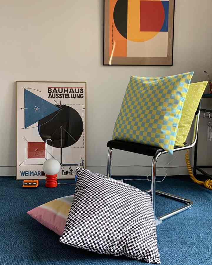 Mid-century modern living room with blue rug, checkerboard cushions, and black chair creating a cozy interior space