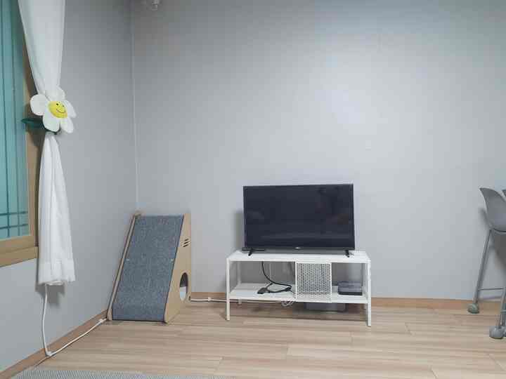 A simple living room with white and natural color tones featuring a cat scratching post and TV stand