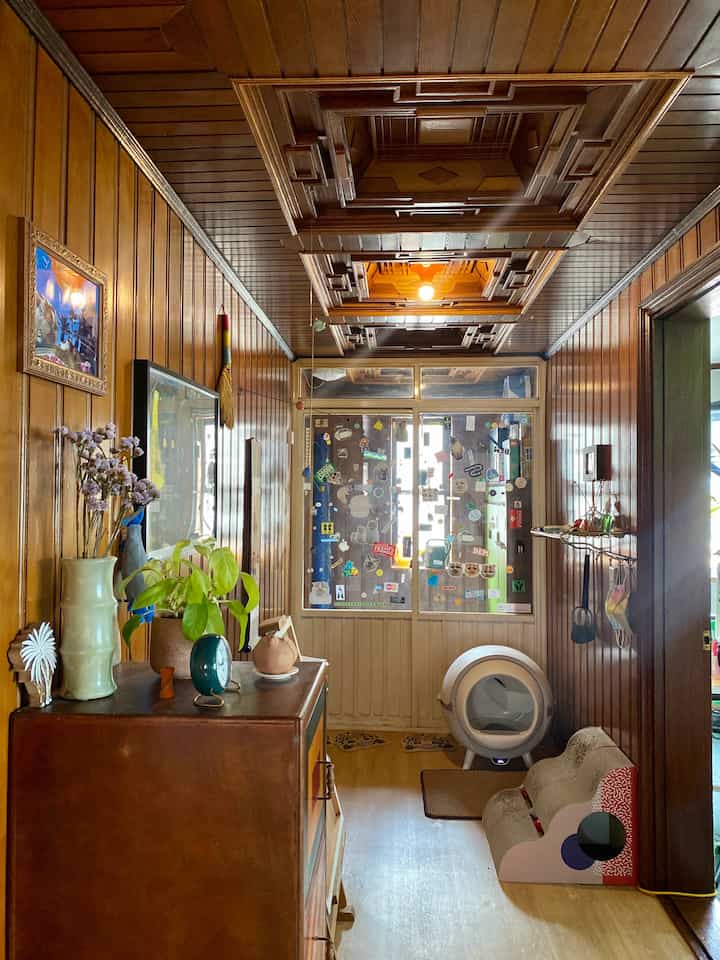 Wood tone entrance featuring a wooden paneled ceiling and walls with a cat litter box and scratching post creating a cozy atmosphere