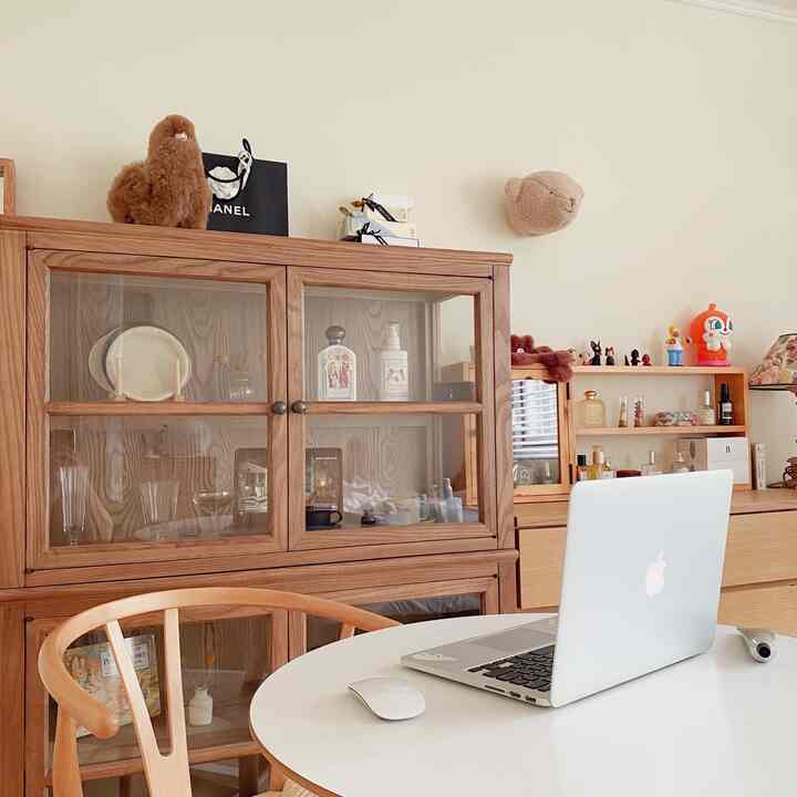 Cozy home office space featuring a round white table and wooden storage cabinets in a vintage wood-toned interior