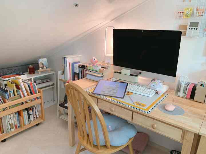 明るいホワイトの背景とウッドトーンのデスクと椅子が置かれた低い天井のコーナーホームオフィス空間