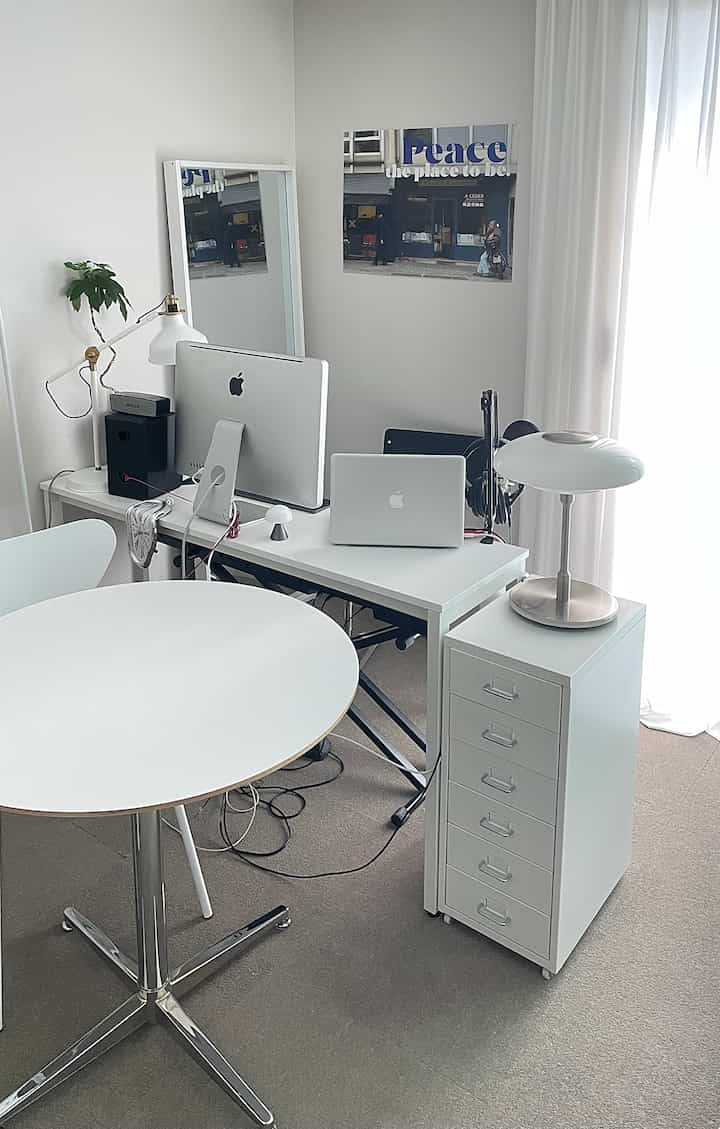 White-toned home office featuring iMac and MacBook in a simple, modern workspace