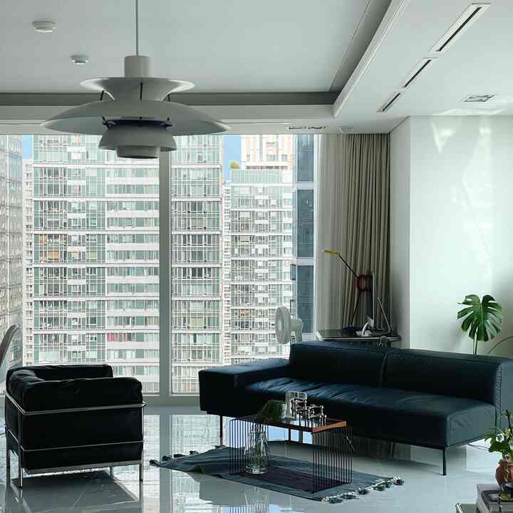 Modern mid-century modern living room with black leather sofa and armchair, white walls and large floor-to-ceiling windows