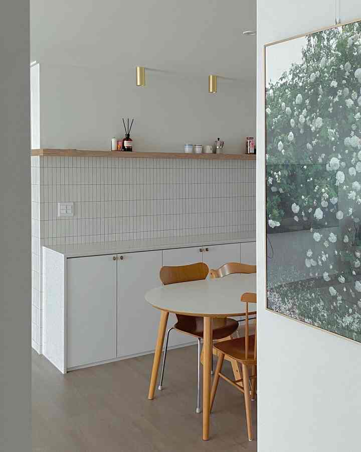 White and wood tone kitchen space featuring a round dining table and chairs, showcasing a clean and modern interior vibe