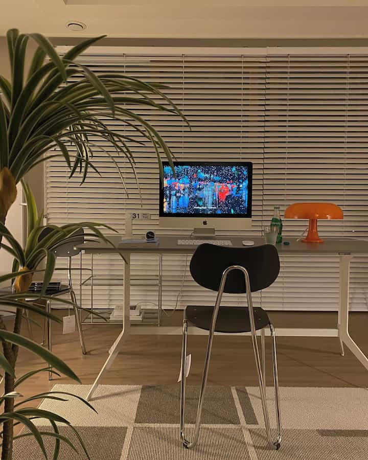 Natural wood tone floor and gray desk in a simple home office featuring a central iMac and office chair