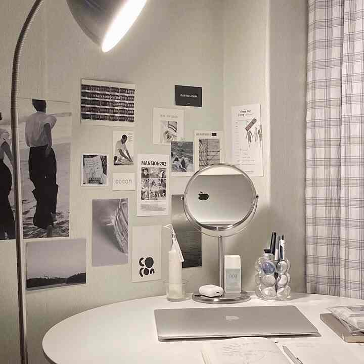 白を基調とした書斎空間、白い楕円形のデスクと多数のモノクロポスターが配置されたモダンでシンプルなインテリア