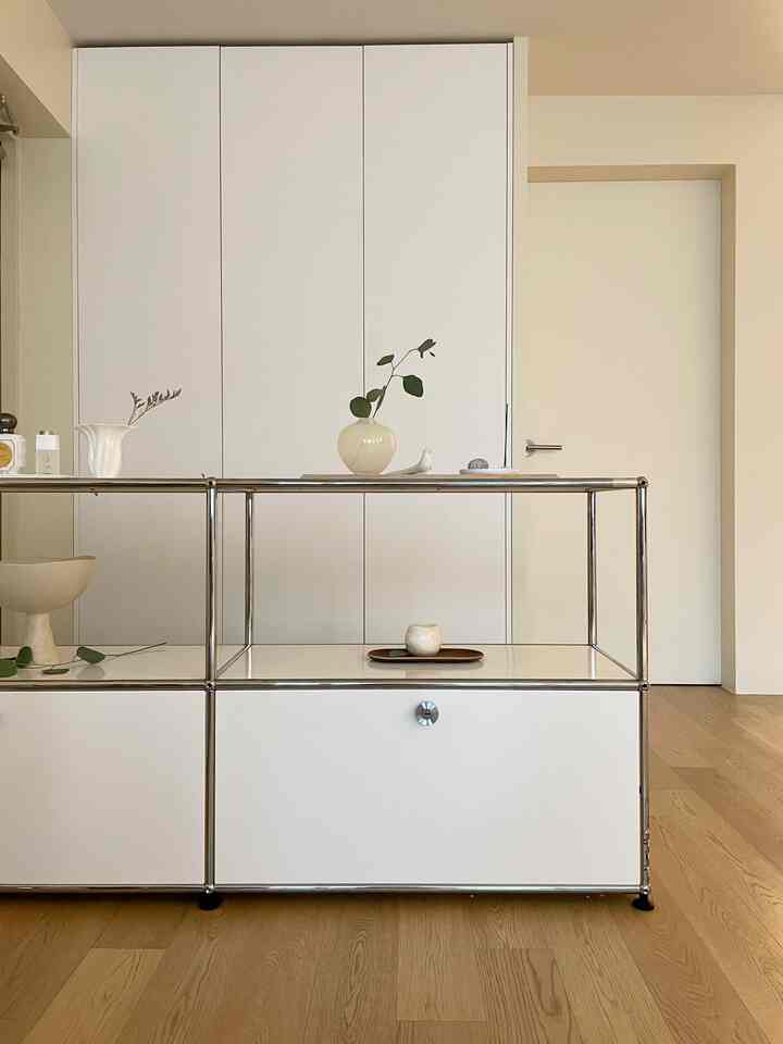 白と木目調の玄関、システム棚の上にオブジェが配置されたシンプルでナチュラルなインテリア