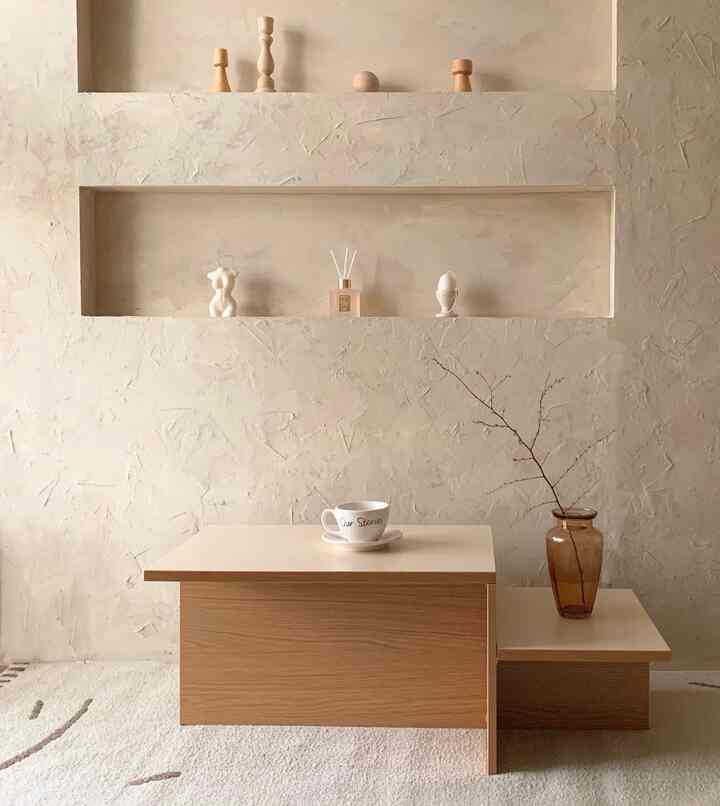 Beige wall and wood tone table featuring decorative objets in a natural and minimal home cafe space