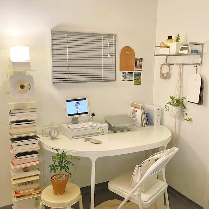 White-toned compact home office featuring a desk, shelves, and plants in a neat workspace