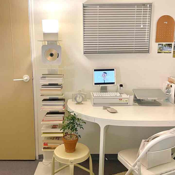 White toned small home office featuring a unique floating bookshelf and simple desk layout with a minimalist and clean atmosphere