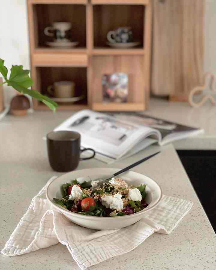 Natural-tone kitchen space with wooden shelves, featuring a plate of salad and a mug creating a cozy home cafe vibe