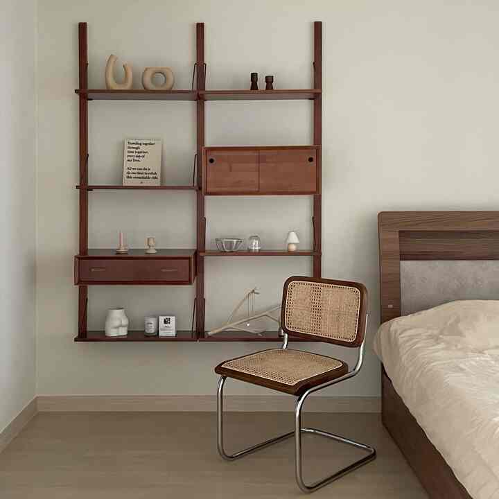 Beige and wood tone bedroom featuring a wall shelf and rattan armchair with cozy natural atmosphere