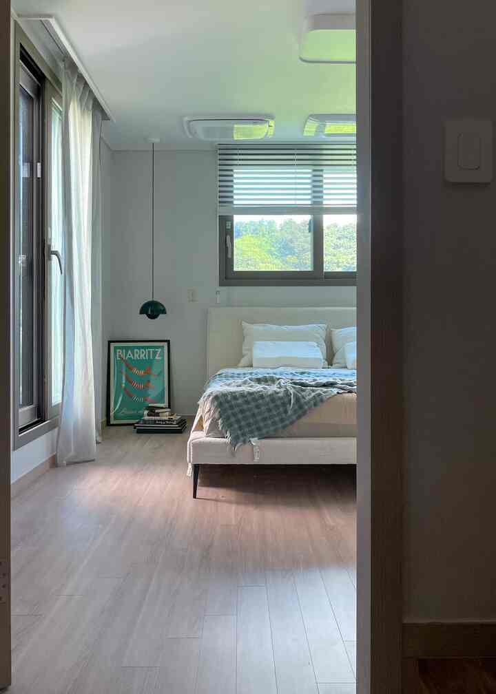 Bright and clean 6-tatami bedroom with natural colors and wood tones, featuring a Boconcept bed and green pendant light