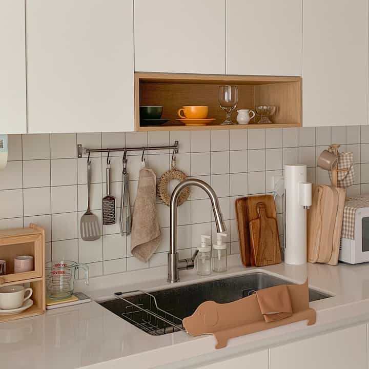 Bright white and wood tone kitchen space featuring a sink and assorted kitchen accessories with cozy autumn atmosphere